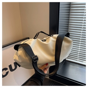 Detail of minimalist cream white oxford dumpling bag with contrast black nylon strap handles
