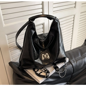 Macro shot of black vintage textured PU leather bag with silver M logo and metal chain detail