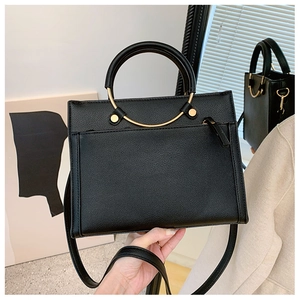 Detail of black pebbled leather handbag with elegant golden metal ring handle
