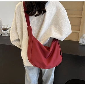 Rear view of a model wearing the large red crescent canvas crossbody bag for daily use