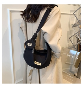 Détail d'un sac bandoulière noir en demi-lune avec un porte-monnaie rond amovible