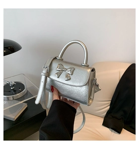 Detailed view of silver bow-knot handbag with leather texture and thin strap