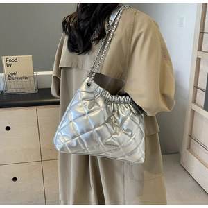 Silver quilted hobo bucket bag with chain strap styled with a beige trench coat