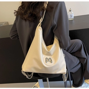 Detail of creamy white leather handbag with silver M logo and decorative metal chains