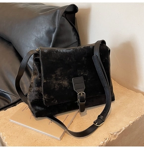 Detailed close-up of retro black matte tote bag with gold buckle on textured stone surface