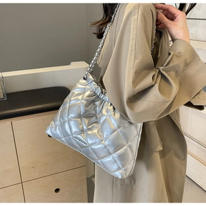 Detail view of silver quilted bucket bag with metallic finish and chain strap on shoulder