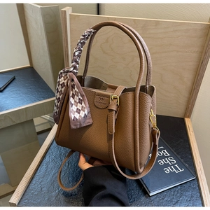 Detailed view of a brown pebbled leather bucket bag with a decorative silk handle scarf