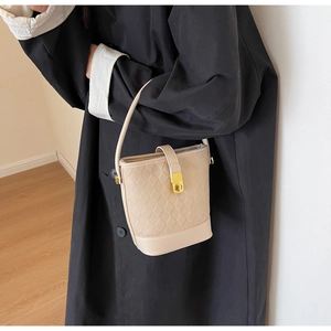 Détails du sac seau beige en cuir matelassé avec fermoir rotatif doré élégant