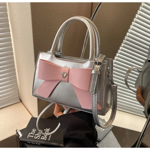 Macro view of silver crossbody bag with a pink leather bow and heart rhinestone detail