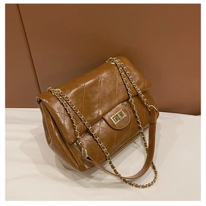 Macro detail of brown quilted leather texture and gold metal twist lock on the bag