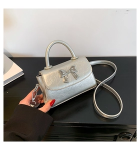 Detailed close-up of metallic silver mini bag featuring a decorative metal bow accent