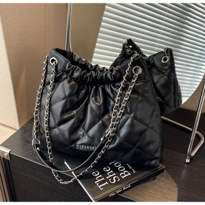 Close-up of quilted black crossbody bucket bag with silver chain and glossy finish