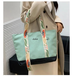 Détail du sac cabas en toile vert menthe avec large bandoulière fleurie sur un modèle