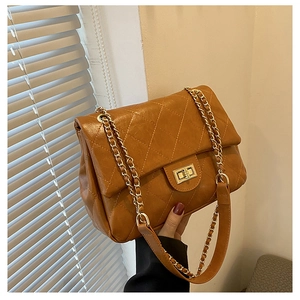 Detailed macro view of brown quilted leather texture and gold metal chain strap on handbag