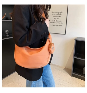 Détail du sac à bandoulière orange en demi-lune avec petit porte-monnaie assorti