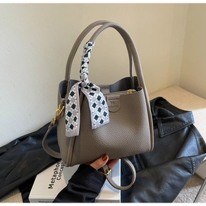 Detail of grey lychee leather bucket bag with silk scarf on handle and shoulder strap