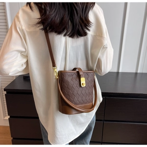 Détail du sac seau marron matelassé avec fermoir doré rotatif et bandoulière réglable