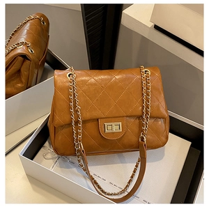 Detailed macro view of quilted brown crossbody bag with gold-tone twist lock closure
