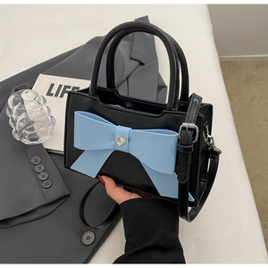 Detail of black leather handbag with blue bow and heart-shaped rhinestone buckle decoration