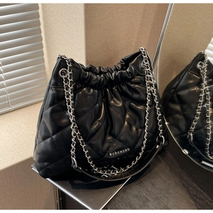 Macro detail of black quilted leather bucket bag with silver chain and drawstring closure