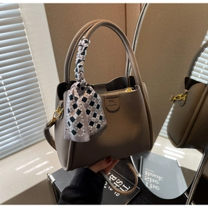 Close-up of lychee grain leather bucket bag with silk scarf handle and golden hardware