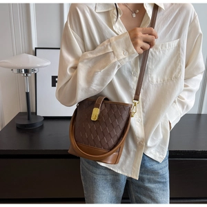 Détail du sac seau marron montrant la texture matelassée et la boucle dorée