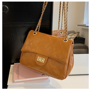 Close-up of caramel quilted leather texture with gold chain strap and metal clasp