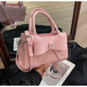 Detailed close-up of a pink handbag with large bow and heart-shaped rhinestone charm