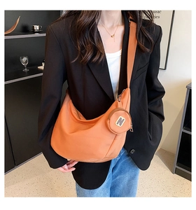 Détail du sac bandoulière orange vif en demi-lune et de la pochette ronde avec logo N