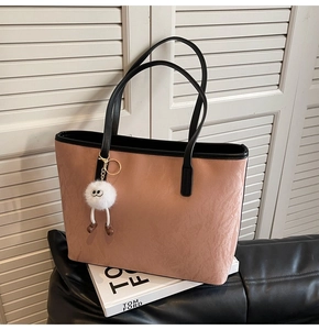 Detail of pink tote bag with black contrast handles and a cute plush doll pendant