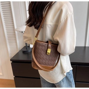 Détail du sac seau marron foncé avec gaufrage en losanges et fermoir rotatif doré