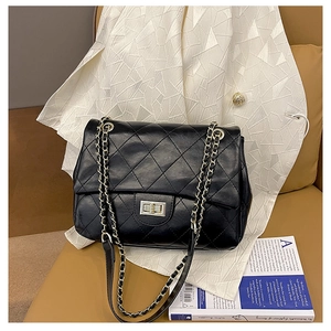 Detail of black quilted leather crossbody bag with metal chain strap and twist lock