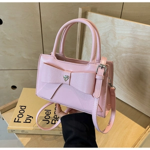 Detail of pink bow handbag featuring a sparkling heart rhinestone and textured leather
