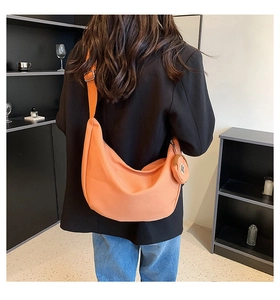 Détail d'un sac demi-lune orange vif avec bandoulière réglable et petit porte-monnaie