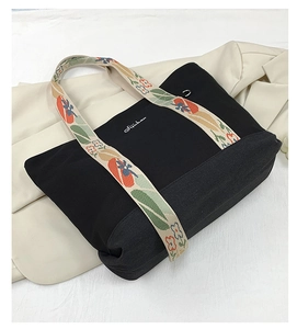 Détail d'un cabas en toile avec bandoulière jacquard florale sur un blazer blanc