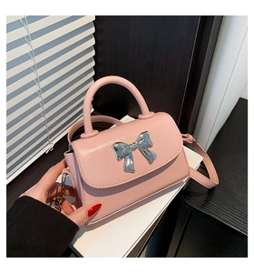 Close-up of pink leather handbag featuring a silver bow buckle and adjustable strap