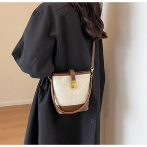 Détail du sac seau crème à texture losange, finitions cuir marron et fermoir doré chic