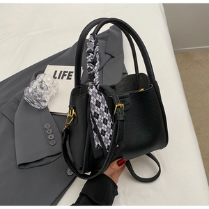 Close-up of black lychee grain bucket bag with checkered scarf and gold hardware