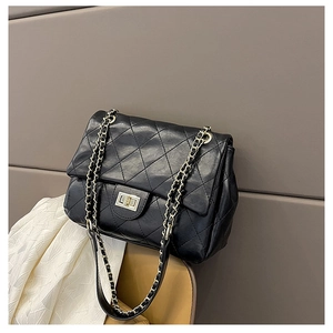 Detail of black quilted leather shoulder bag with gold-tone chain strap and twist lock