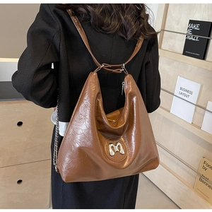 Detail of large brown tote bag showing wrinkled leather texture and metallic M logo