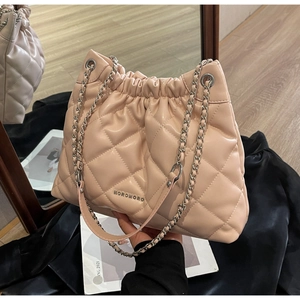 Detailed close-up of quilted nude pink leather texture and silver chain strap on bucket bag