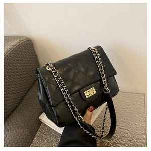 Detail of black quilted chain bag featuring gold metal hardware and diamond texture