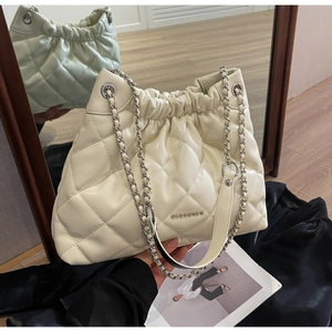 Detailed view of white quilted bucket bag with silver chain strap and drawstring closure