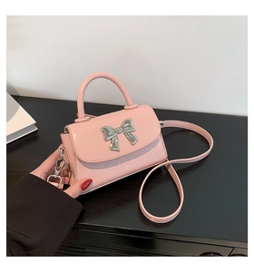 Detail of pink mini square bag with silver metal bow and textured leather finish
