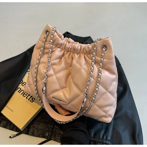 Detail of light pink quilted leather bucket bag with silver logo and chain on a jacket