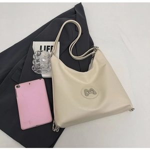 Detail of cream white tote bag with silver M logo and chain strap on a blazer