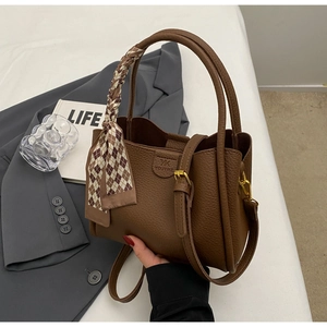 Detail of dark brown lychee textured handbag featuring a stylish plaid silk scarf handle