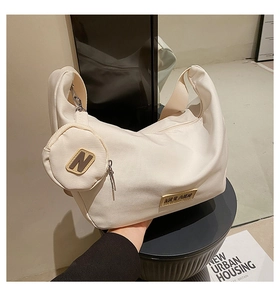Détail du sac hobo en toile beige avec pochette amovible et logo métallique chic