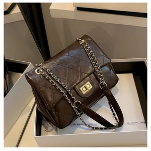 Detail of coffee quilted chain bag with gold twist lock on elegant gift box