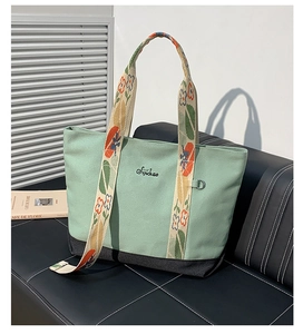Détails de broderie florale sur la sangle et sac cabas en toile menthe avec logo noir